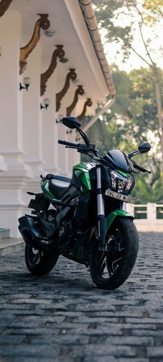 a green motorcycle parked in front of a white building