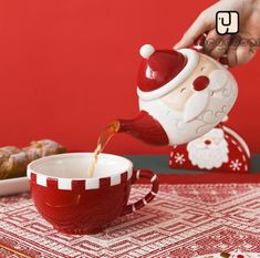 a person pouring tea into a cup on top of a red and white table cloth