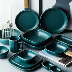 a group of teal colored dishes and cups on a table with an image in the background