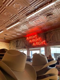 several hats sit in front of a sign that reads alright, alright and right on the ceiling