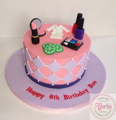 a pink and purple birthday cake with various items on it