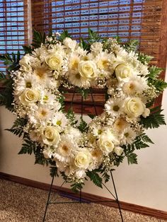 a heart shaped wreath with white flowers and greenery