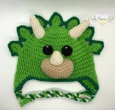 a crocheted green hat with black eyes and horns