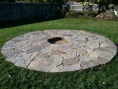 a stone fire pit in the middle of a yard