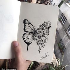 a drawing of a butterfly with flowers on it's wings is held up in front of the camera