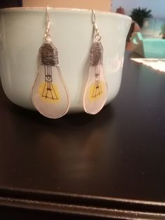 a pair of light bulbs are sitting on a table next to a bowl with a spoon in it