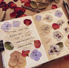 an open book with flowers and writing on it