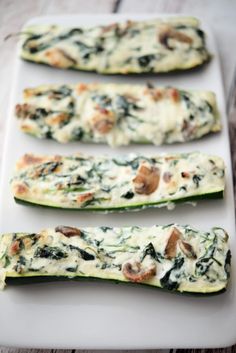 three zucchini boats with spinach and mushrooms on them sitting on a white plate