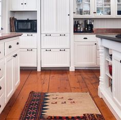 a kitchen with white cabinets and wood flooring is pictured in this image from the front view