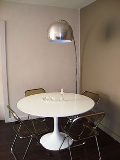 a white table and chairs in a room with a lamp on the wall behind it