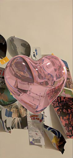 a pink heart shaped object surrounded by pictures and rainbows in the sky above it