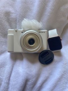 a white camera sitting on top of a bed next to a black and white object