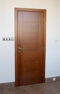 a wooden door in a room with tile flooring and white walls on the wall