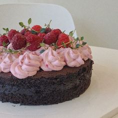 a chocolate cake topped with whipped cream and raspberries