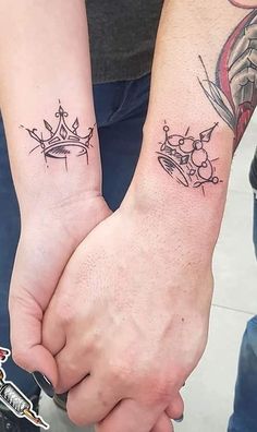 two people holding hands with tattoos on their arms