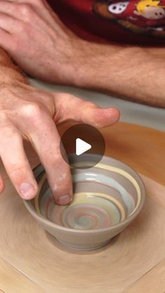 a man is making a bowl on a wooden table with his hand over the bowl