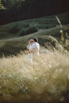 a man and woman are standing in the tall grass with their arms around each other