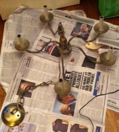 a bunch of bells on top of a newspaper with some wires attached to them and one bell is hanging from the ceiling