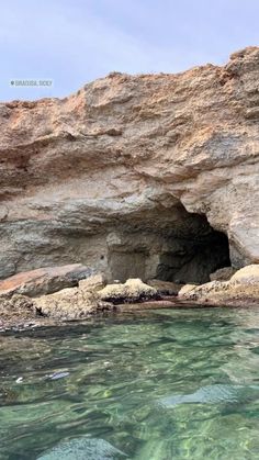 the water is crystal clear and blue in this rocky beach area with an ocean cave