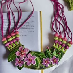 a book with flowers and leaves on it next to a necklace made out of beads