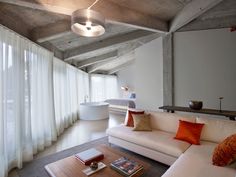 a living room filled with furniture and a large window covered in white drapes next to a bathtub