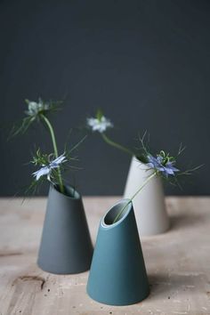 three vases with flowers in them sitting on a wooden table next to each other