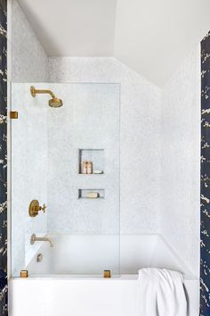 a white bath tub sitting under a window next to a wall mounted faucet