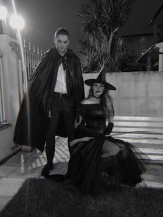 a man standing next to a woman in a witch costume