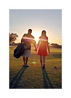 two people holding hands while standing in the grass with golf bags on their shoulders and walking towards the camera