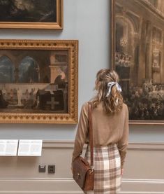 a woman looking at paintings in a museum