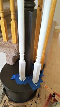 some white pillars and blue tape are on the floor in front of a stair case