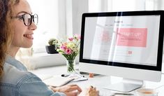 a woman sitting in front of a computer screen with the word start up on it