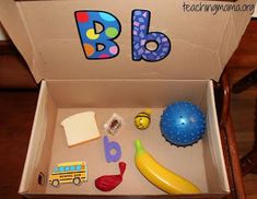 an open box with toys in it and the letters b, d, e, and f