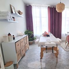 a treatment room with tables and chairs in the corner, two plants on the far wall