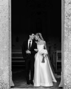 black and white photo of bride and groom kissing in church doorway with pews behind them