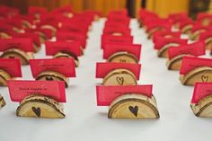 place cards are placed on wooden slices with hearts in the center and red envelopes attached to them