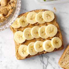 peanut butter and banana slices on top of a piece of bread next to a bowl of peanut butter