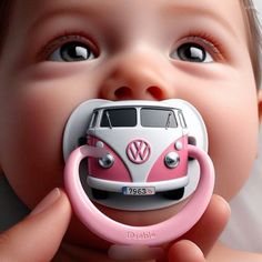 a baby holding a pink and white toy in it's mouth with the word vw bus on it