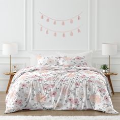 a bed with pink and white flowers on it in a room next to a wall