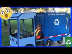 a child in a blue garbage truck with a green recycler behind it