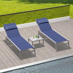 two lounge chairs sitting on top of a wooden deck next to a pool with water