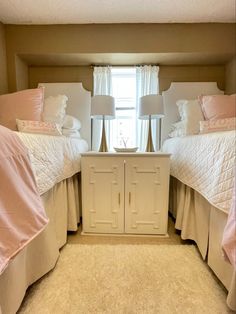 there are two beds in the room with pink comforters on each bed and white linens on the floor