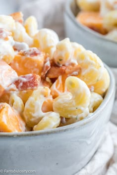 two bowls filled with macaroni and cheese covered in bacon