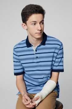 a young man sitting on top of a chair with an arm cast in his hand