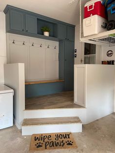 a garage with white cabinets and gray walls, an area rug that says wipe your paws