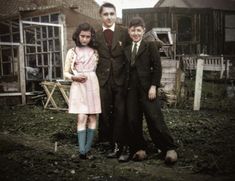 an old photo of three people standing next to each other in front of some houses