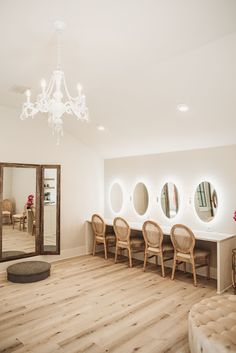 a room with chairs and mirrors on the wall, in front of a chandelier