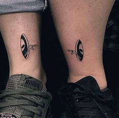 two people with matching tattoos on their legs, one has an alien head and the other is