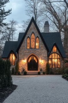 a large stone house with arched windows and lights on it's front door is lit up at night