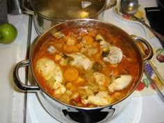 a large pot filled with food on top of a stove next to an orange and green apple